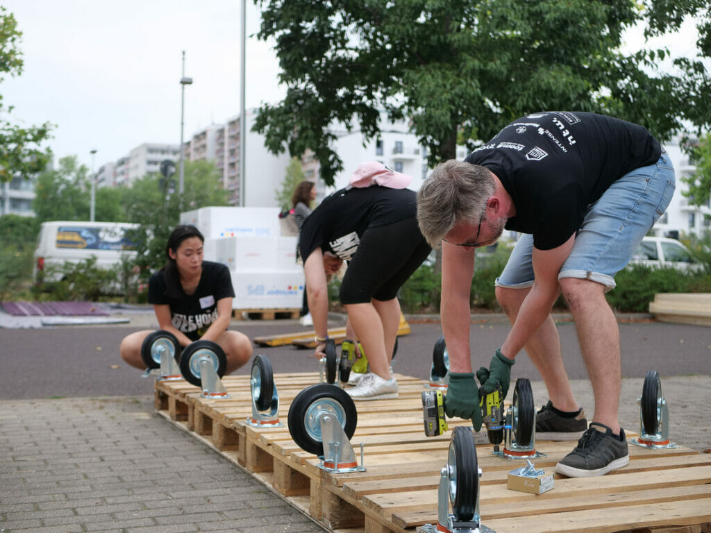 Der Kölner Verein hat im August 2022 einen Weltrekord in Berlin aufgestellt: 100 Freiwillige beteiligten sich am eintägigen Bauprojekt und stellten zehn der mobilen Wohncontainer für wohnungslose Menschen her.