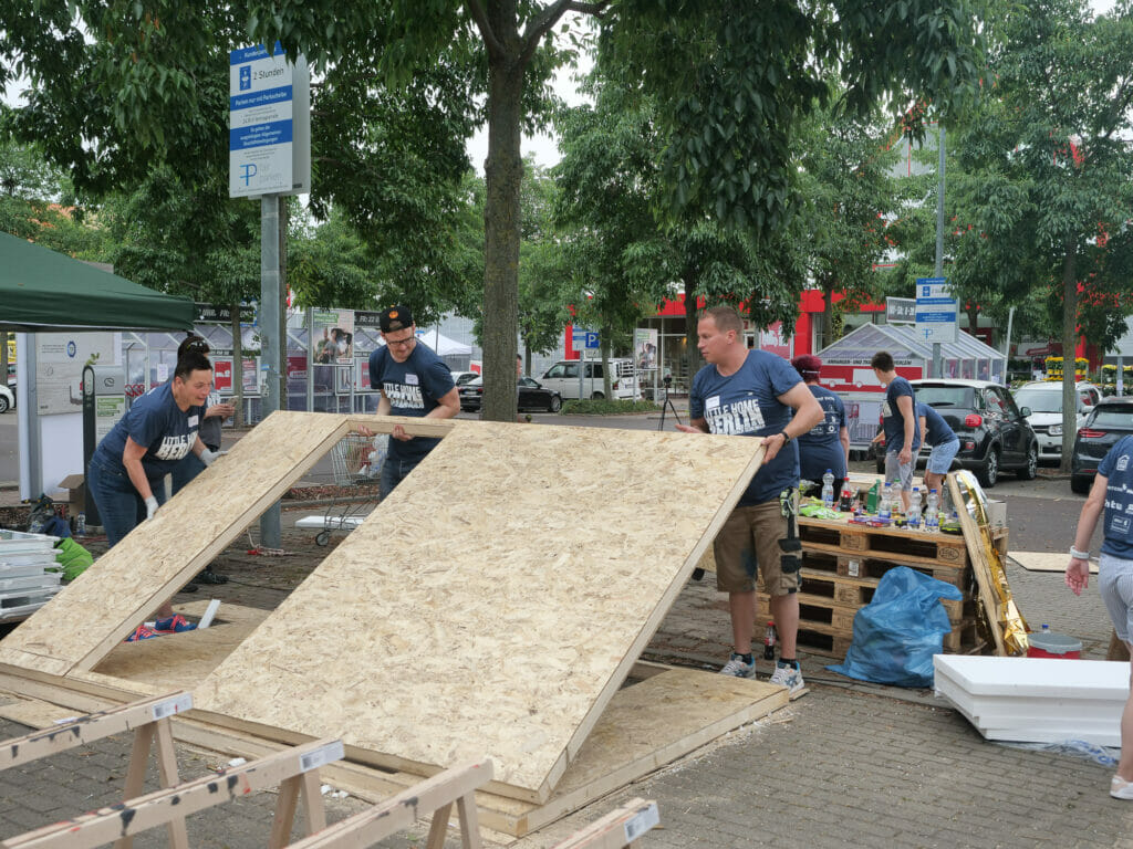 Der Kölner Verein hat im August 2022 einen Weltrekord in Berlin aufgestellt: 100 Freiwillige beteiligten sich am eintägigen Bauprojekt und stellten zehn der mobilen Wohncontainer für wohnungslose Menschen her.