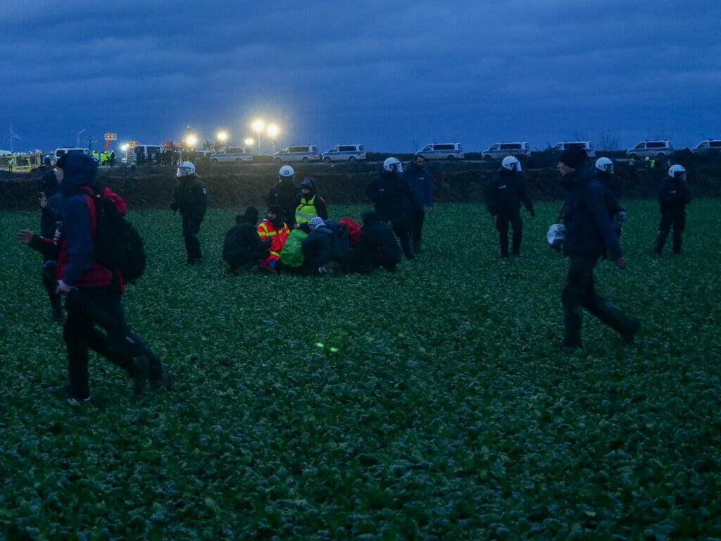 Demosanitäter:innen vor einer Polizeikette.