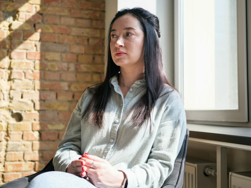 Mariia Stetsyuk sitzt in einem Stuhl. Sie leitet die Gruppenangebote für Angehörige des Veteran Hub in Kyjiw.